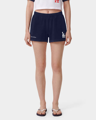 The LA Serif Disco Short in Dark Navy/White is a pair of super-short, cotton fleece shorts featuring Sports&Rich and LA logos on the front, made in the USA and displayed laid flat on a white background.