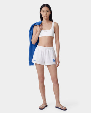 LA Serif Disco Short in White/Team Blue, featuring a blue LA logo and Sporty & Rich text on the front, crafted from athletic cotton fleece with a super-short length, made in the USA and laid flat on a white background.