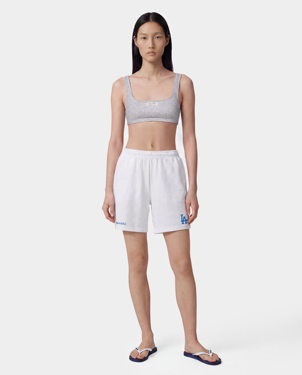 Dodgers Serif Gym Short - White/Team Blue, white athletic jersey shorts featuring Sporty & Rich and LA logos in team blue on the front, made from 100% cotton with an elastic waistband, displayed on a gray background.