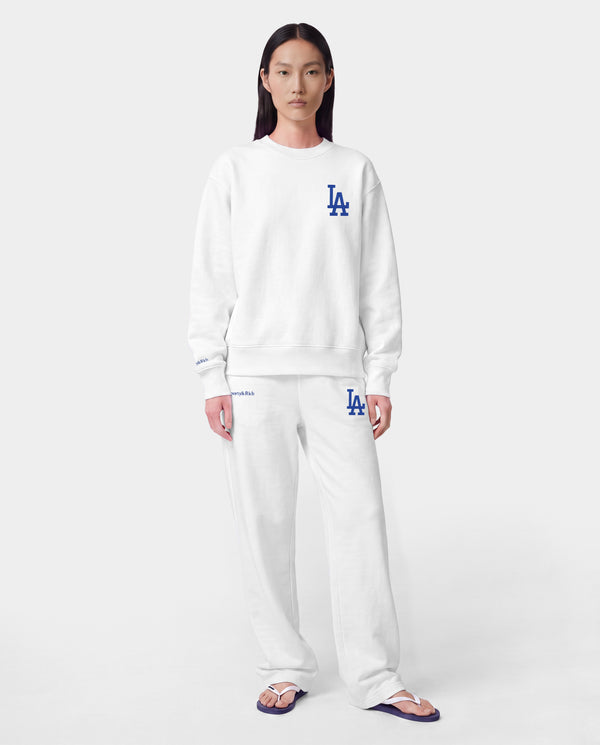 LA Serif Wide Sweatpant - White/Team Blue, crafted in Portugal from 100% cotton, features a wide-leg silhouette with blue LA and Sports Rich logos and is displayed on a plain light gray background.