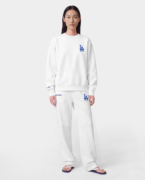 LA Serif Wide Sweatpant - White/Team Blue, crafted in Portugal from 100% cotton, features a wide-leg silhouette with blue LA and Sports Rich logos and is displayed on a plain light gray background.
