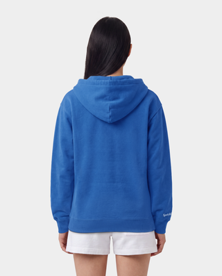 LA Serif Zip Hoodie in Team Blue/White, featuring a white LA logo on the left chest, front pockets, and a zip closure. Crafted from 100% cotton with an oversized fit and displayed laid flat on a white background.