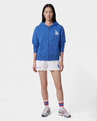 LA Serif Zip Hoodie in Team Blue/White, featuring a white LA logo on the left chest, front pockets, and a zip closure. Crafted from 100% cotton with an oversized fit and displayed laid flat on a white background.