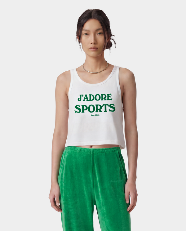 Jadore Baby Tank - White/Kelly: A white cropped tank top featuring bold green "J’ADORE SPORTS" text on the front, crafted from 100% cotton and shown against a plain background.