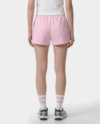 The Fitness 94 Disco Short in Laffy/White features light pink cotton fleece, an elastic waistband, and a Sporty & Rich logo on the bottom right leg. Made in the USA, it is displayed on a gray background.