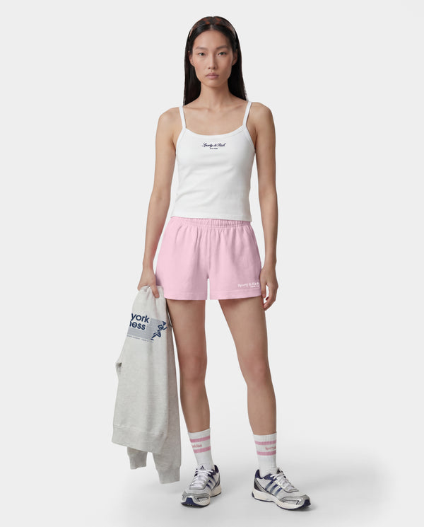 The Fitness 94 Disco Short in Laffy/White features light pink cotton fleece, an elastic waistband, and a Sporty & Rich logo on the bottom right leg. Made in the USA, it is displayed on a gray background.