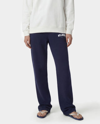 Wellness Ivy Wide Sweatpant in Dark Navy/White, featuring "WELLNESS" text on the left pocket, made from 100% cotton with an elastic waistband, displayed flat on a white background.