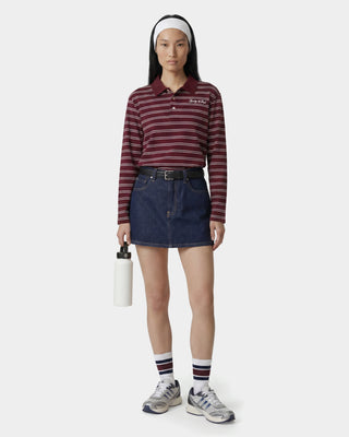 Person wearing a striped shirt, denim skirt, and holding a water bottle on a white background