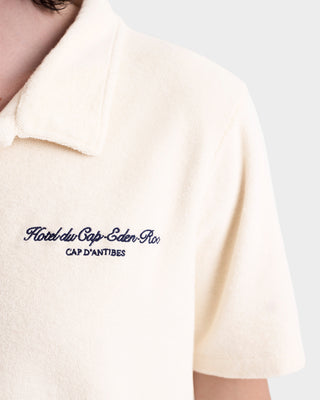 Close-up of the Eden Script Terry Polo in Cream/Navy, crafted in Portugal from 100% cotton terry, featuring Hôtel du Cap-Eden-Roc, CAP D’ANTIBES embroidered on the chest.