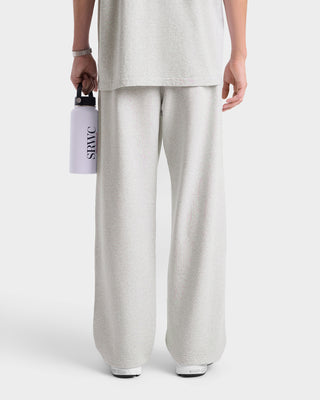 Person wearing light gray pants holding a white water bottle with 'Sraw' branding on a white background