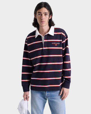 Person wearing a navy and red striped long-sleeve polo with a white collar on a light gray background