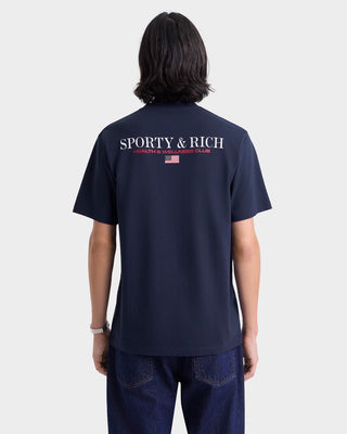 Person wearing a navy blue t-shirt with 'Sporty & Rich' logo on the back, standing against a white background.