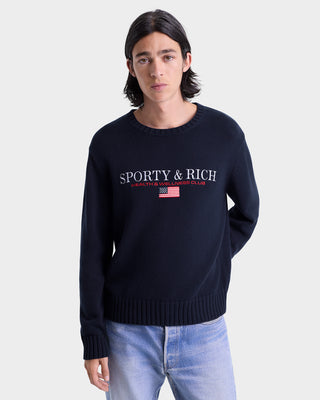 Person wearing a navy blue sweater with 'Sporty & Rich' branding on a white background
