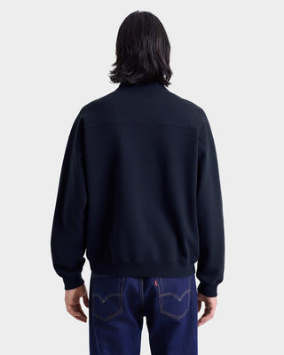 Person wearing a black jacket and blue jeans on a white background