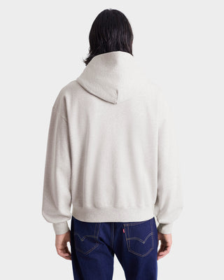 Person wearing a beige sweater and blue jeans on a white background