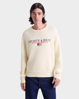 Person wearing a cream sweater with 'Sporty & Rich' logo on a white background