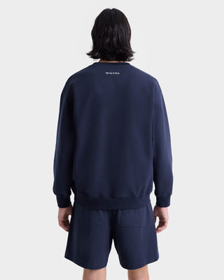 Person with shoulder-length dark hair wears a navy sweatshirt and Eden Crest Gym Short - Navy/White, shown from the back against a plain background.