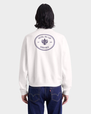 Person wearing the Eden Crest Quarter Zip - White/Navy, featuring the Hotel du Cap Eden-Roc logo on the back, viewed from behind.