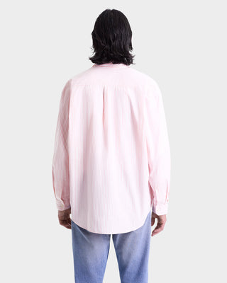 Person with medium-length dark hair wearing the Eden Script Oversized Shirt in pink/white thin stripe and blue jeans, shown from the back.