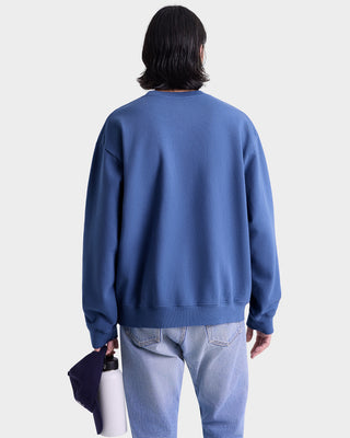 Person wearing a blue sweatshirt and light blue jeans against a white background