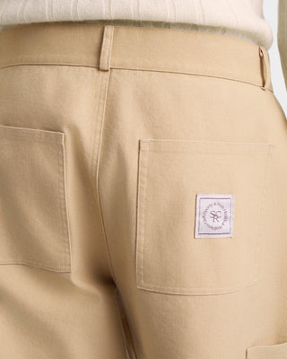 Beige pants with a brand label on the pocket