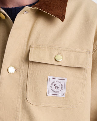 Close-up of a beige jacket with a brown collar and a visible brand label.