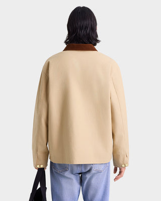 Person wearing a beige jacket on a white background