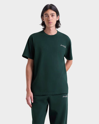 Person wearing a green t-shirt and pants with a brand logo on a white background