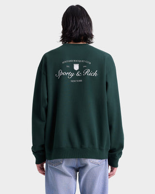 Person wearing a green sweatshirt with 'Sporty & Rich' branding on the back against a white background