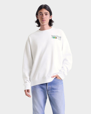 Person wearing a white sweatshirt with a logo on a plain background