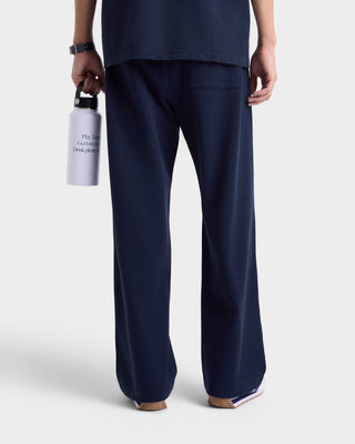 Person wearing navy blue pants holding a white bag with text on a light gray background