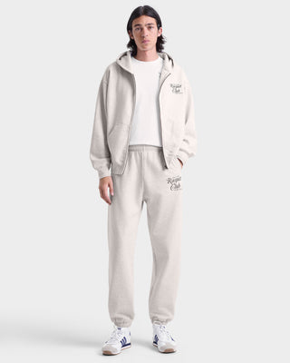 Person wearing a beige tracksuit with brand logo on a white background