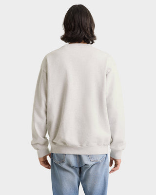 Person wearing a light gray sweatshirt and blue jeans on a white background