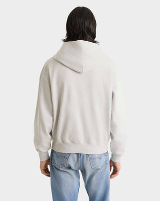 Person wearing a light gray hoodie and blue jeans on a white background