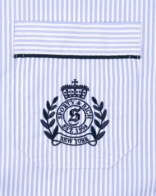 Close-up of a blue and white striped shirt pocket with a logo and text.