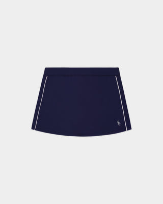 Alia SRC Court Skirt in Dark Navy/White, featuring white piping along the sides, built-in shorts, and sweat-wicking fabric, displayed on a plain white background.