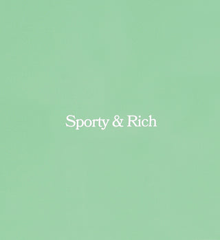 The Serif Logo Court Skirt in Washed Kelly/White features a pale green hue with Sporty & Rich in white, centered in a serif font, echoing classic tennis style with colored stripes and an elastic waistband.