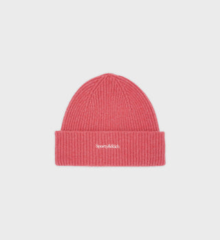 Serif Logo Beanie - Strawberry: A pink ribbed knit beanie featuring a folded brim and “Sporty & Rich” embroidered in white on the front, crafted from Caregora® and responsibly sourced angora for a soft, sustainable feel.