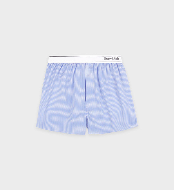 The Serif Logo Boxer Short in light blue and white stripes, featuring an elastic waistband, is made in Portugal by Sporty & Rich and shown on a gray background.