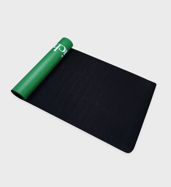 Black yoga mat with green edge on a light gray background