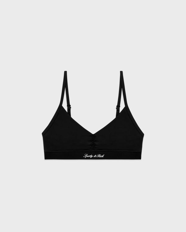 Signature Logo Mini Sports Bra - Black/White, crafted from soft nylon spandex with thin adjustable back straps and a printed logo on the band, displayed on a light gray background.
