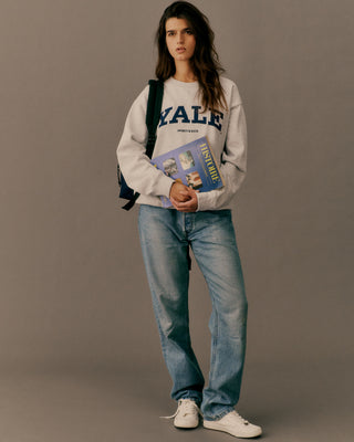 Person wearing a Yale sweatshirt holding a book against a plain background