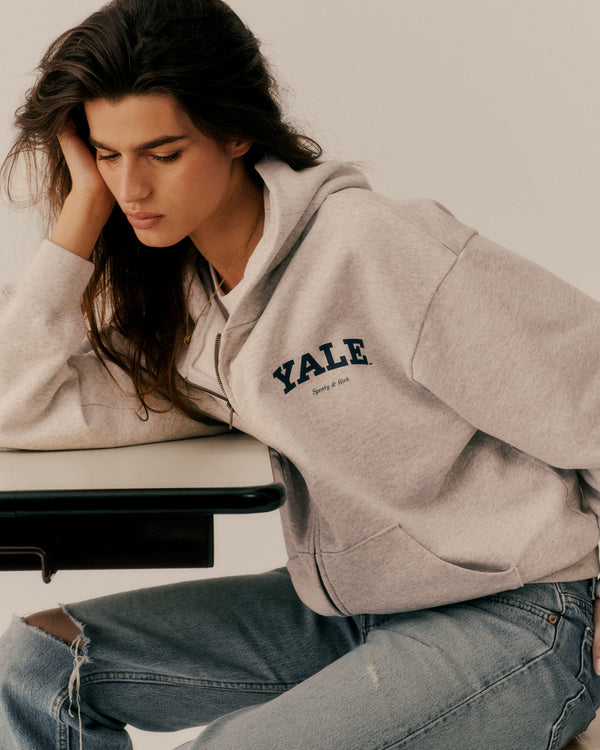 Person wearing a gray hoodie with 'Yale' logo sitting on a bench.