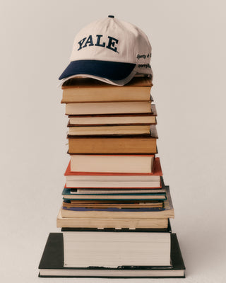 Stack of books with a Yale cap on top against a plain background