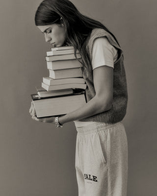 Person holding a stack of books against a plain background