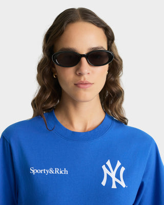 Person wearing a blue sweatshirt with Sporty&Rich and New York Yankees logos on a white background