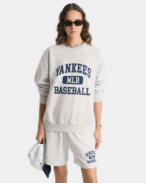 Person wearing a Yankees baseball sweatshirt and shorts on a white background