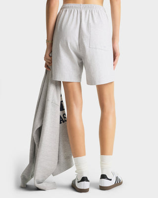 Person wearing light gray shorts with a plain background