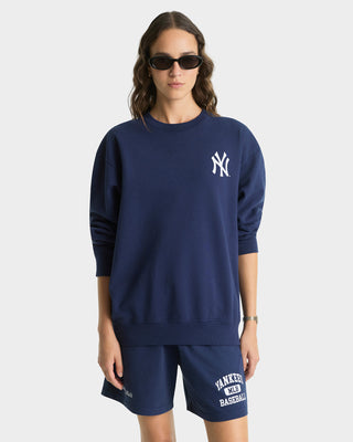 Person wearing a navy blue sweatshirt with a logo and matching shorts on a white background