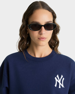 Person wearing a navy blue sweatshirt with a logo, wearing black sunglasses.